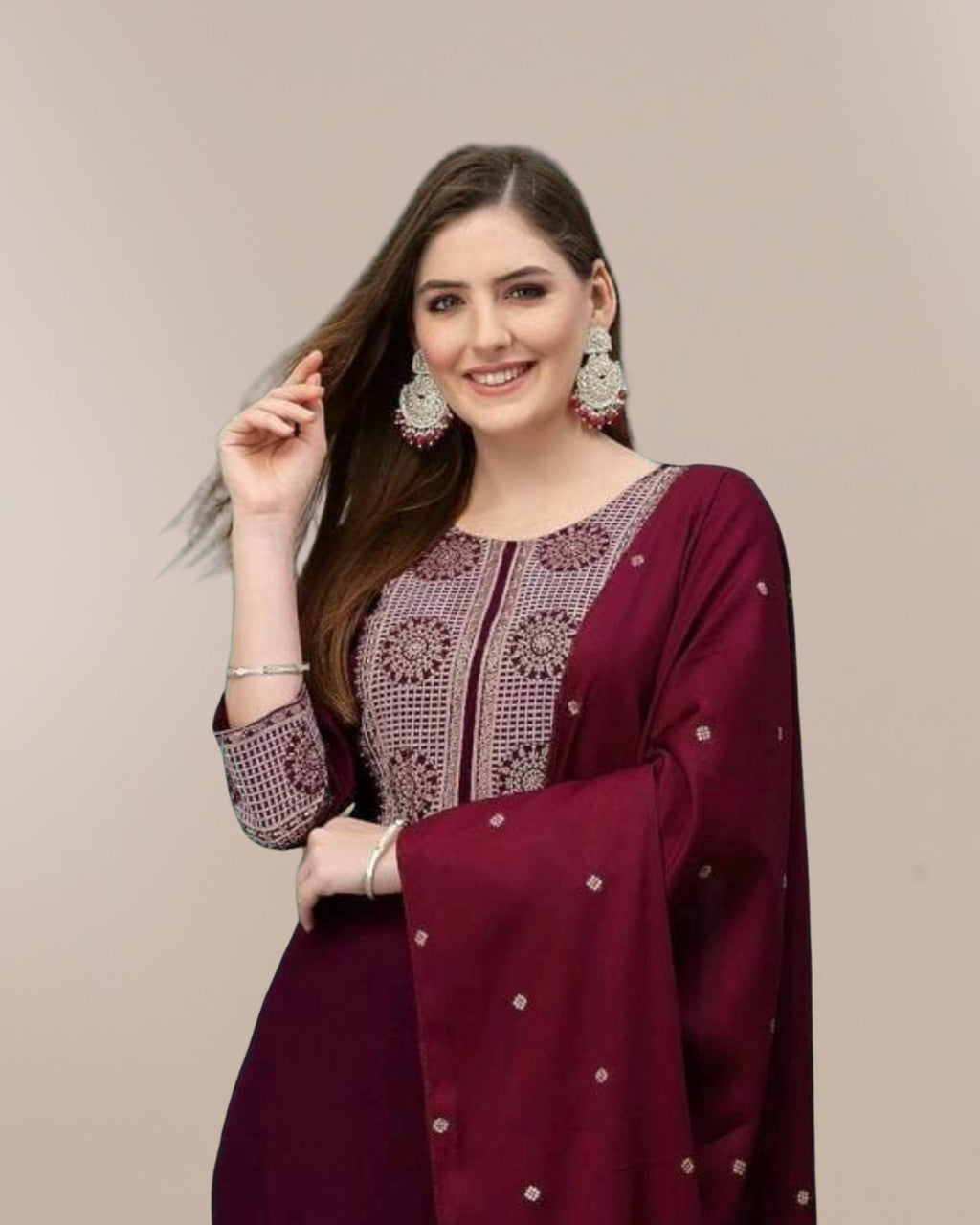 Woman wearing a maroon traditional outfit with intricate designs on a beige background