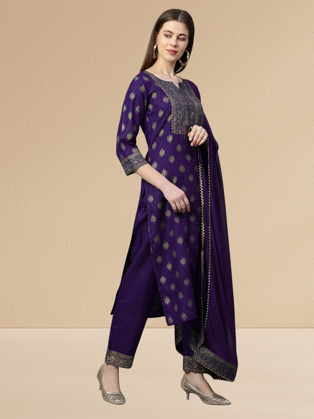Woman wearing a deep purple cotton blend kurta set with gold embroidery on the yoke and a matching dupatta with gold lace trim.