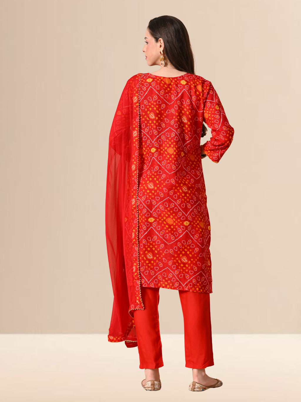 Woman wearing a red traditional outfit with a patterned dupatta on a beige background