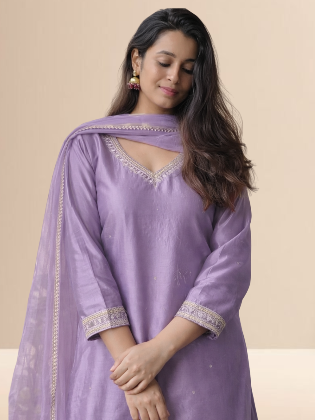 Woman wearing a lavender cotton blend kurta set with delicate lace work on the neck and sleeves, paired with a matching dupatta.
