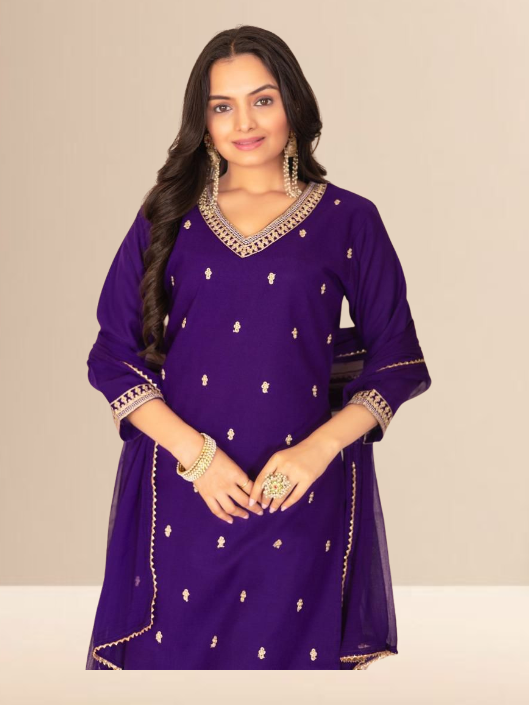 Woman wearing a royal purple kurta set with gold embroidery on the neck and sleeves, paired with trousers and a dupatta.