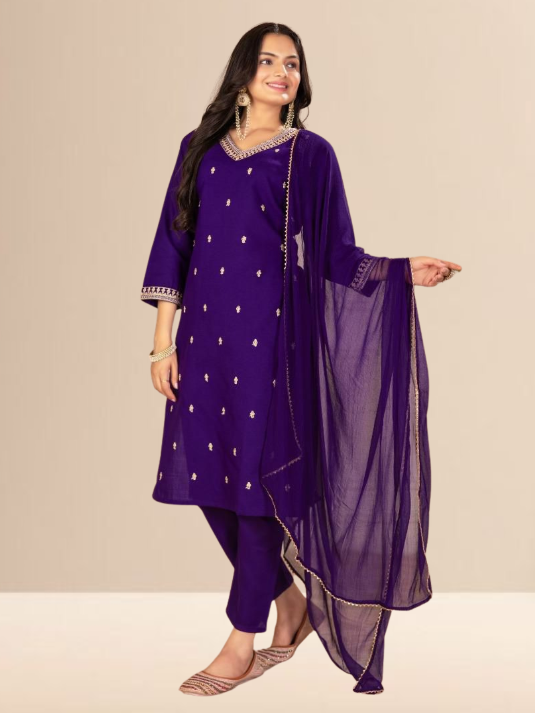 Woman wearing a royal purple kurta set with gold embroidery on the neck and sleeves, paired with trousers and a dupatta.