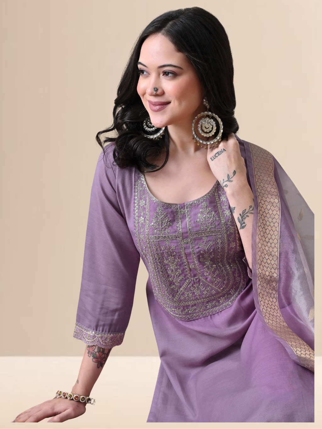 A woman wearing a mauve cotton blend kurta set with golden embroidery on the neck and a floral dupatta.