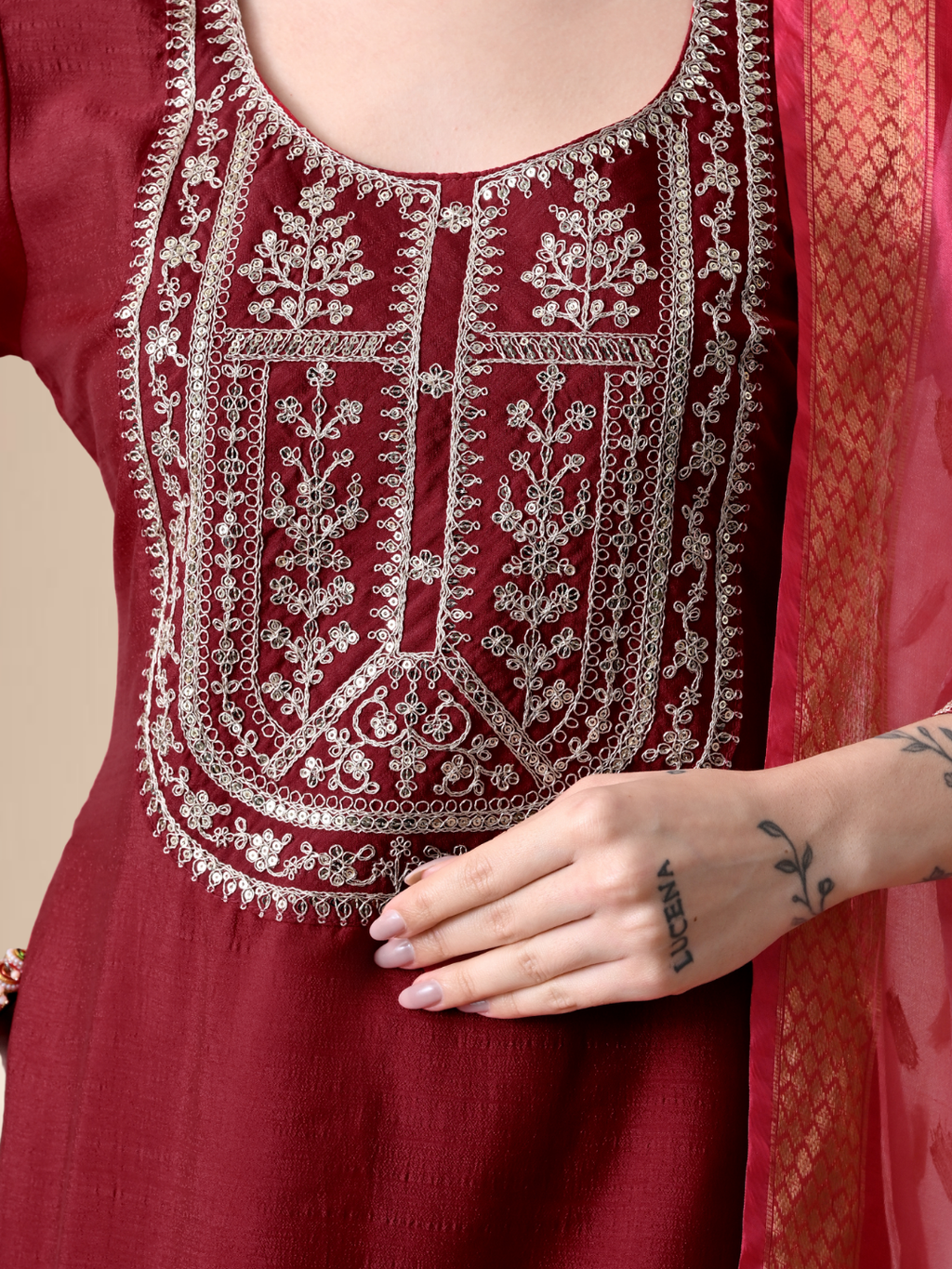 A woman wearing a maroon straight-cut cotton blend kurta with ivory yoke embroidery, matching pants, and a pink floral dupatta.