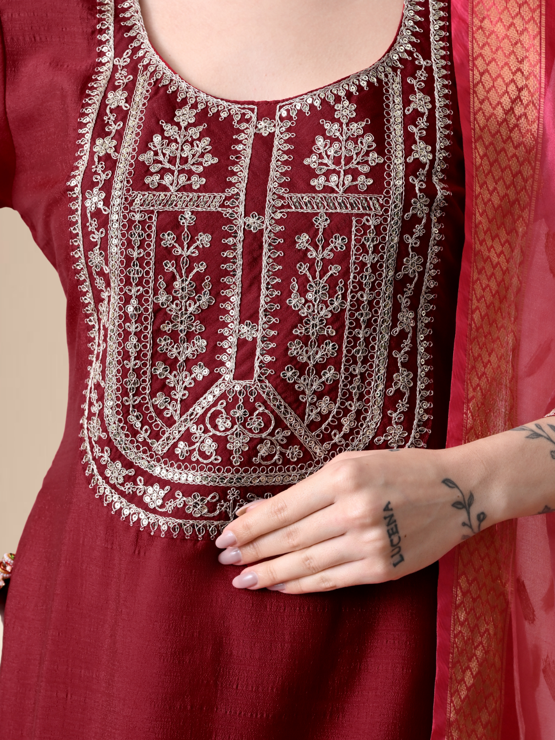 A woman wearing a maroon straight-cut cotton blend kurta with ivory yoke embroidery, matching pants, and a pink floral dupatta.