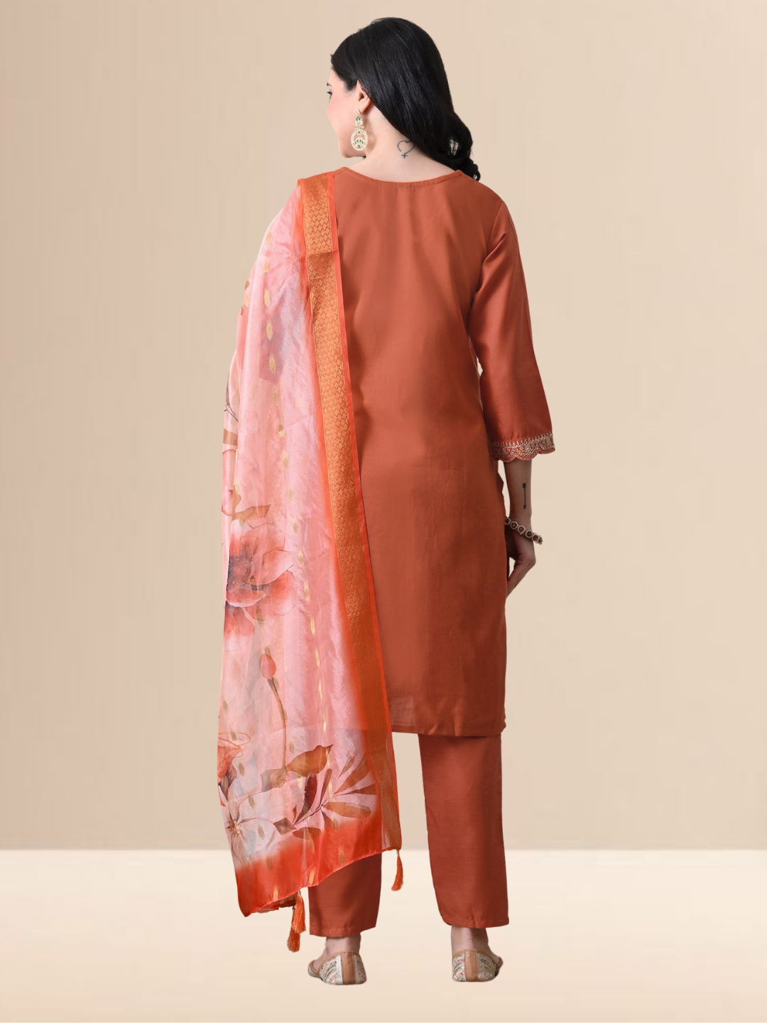 A woman wearing a rust orange straight-cut cotton blend kurta with ivory embroidery on the neck, matching pants, and a floral printed dupatta.