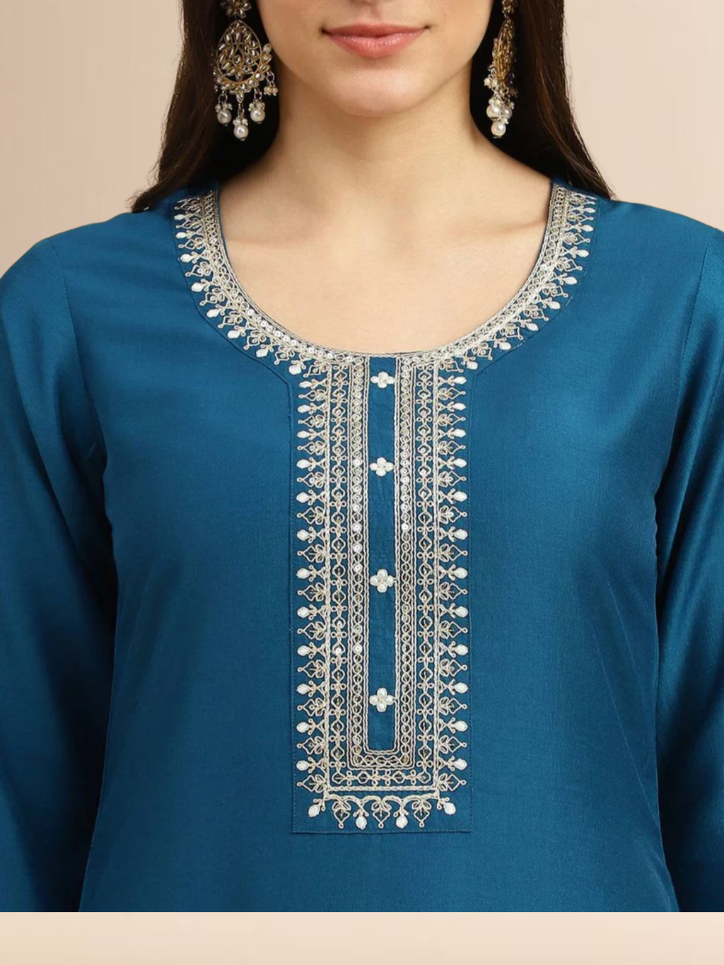 Woman wearing a teal blue Cotton blend kurta with silver embroidery on the neck, matching pants, and a white floral printed dupatta.