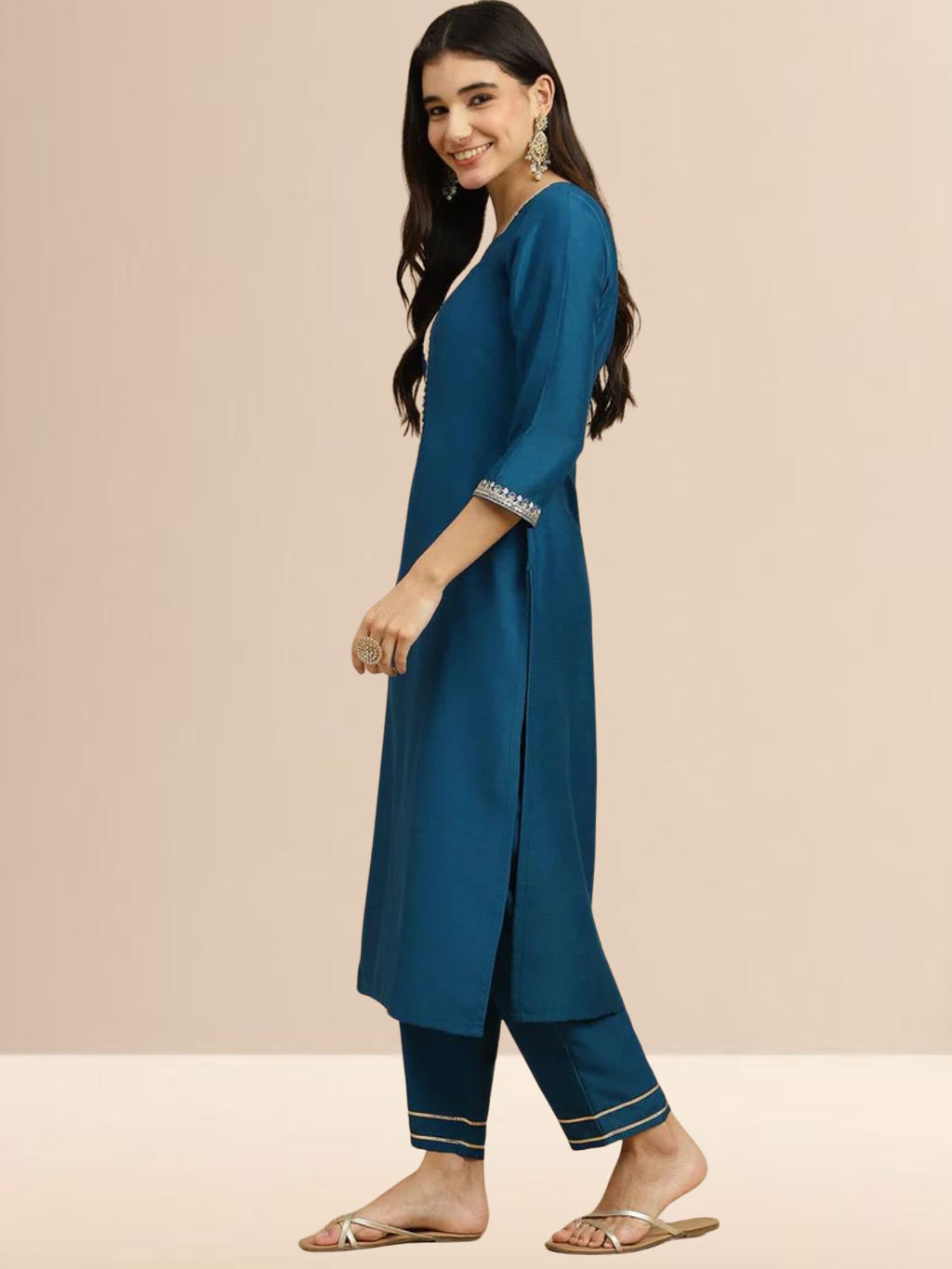 Woman wearing a teal blue Cotton blend kurta with silver embroidery on the neck, matching pants, and a white floral printed dupatta.