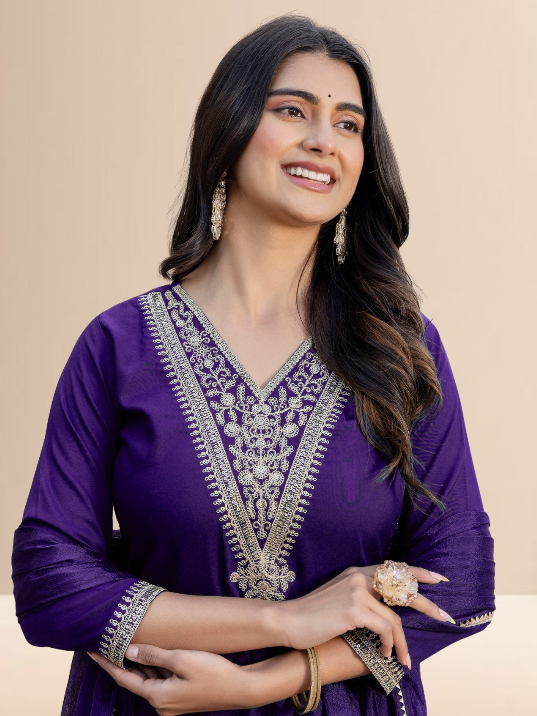 Woman wearing a purple traditional outfit with silver embroidery on a beige background