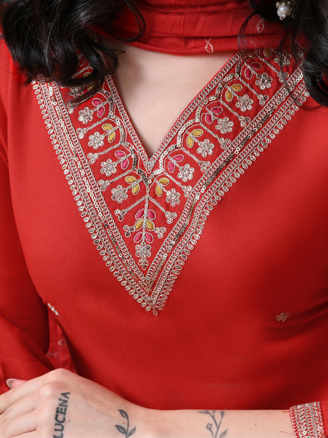 A woman wearing a red straight-cut cotton blend kurta with V-neck embroidery, matching trousers, and a red dupatta.