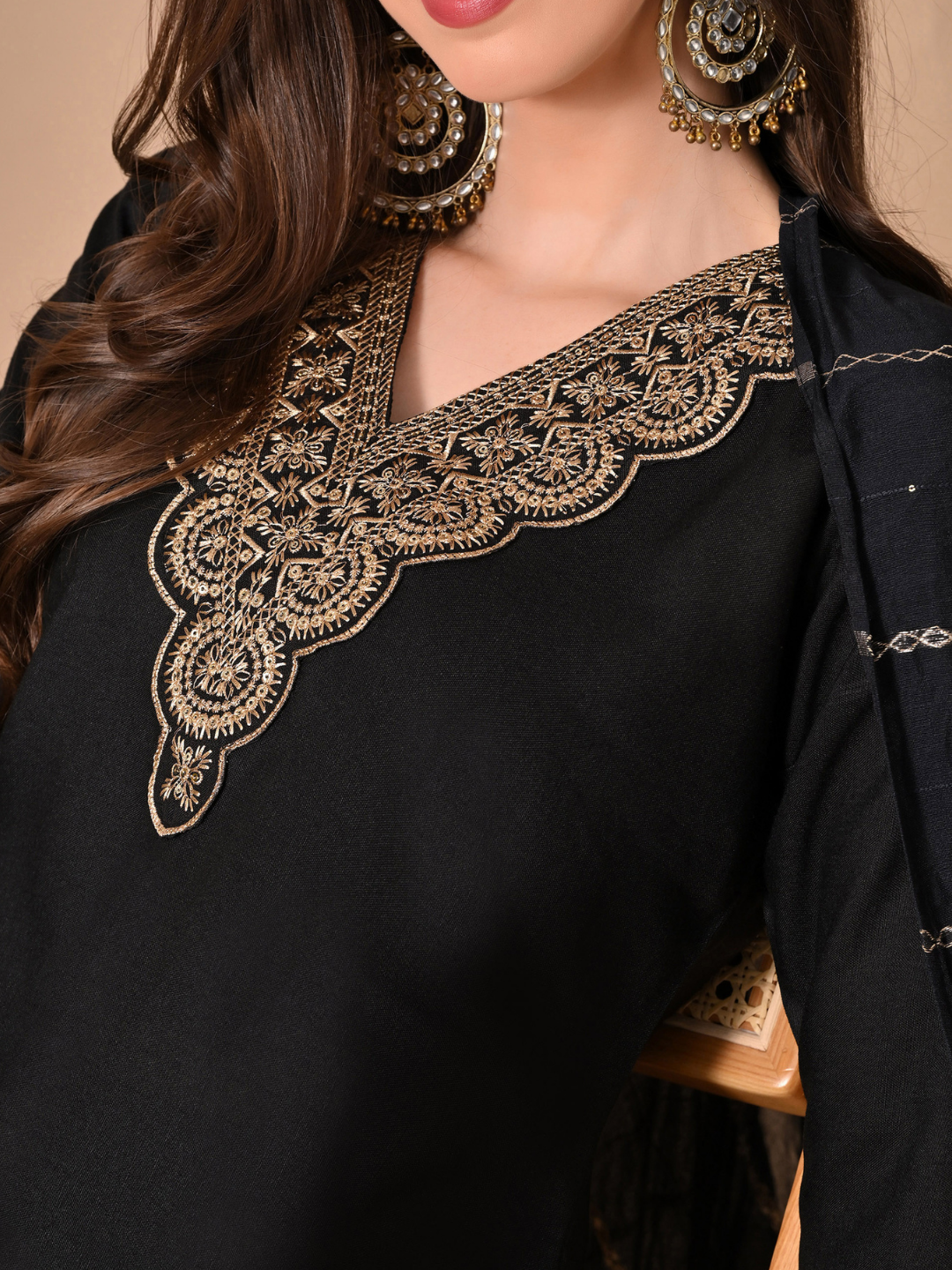 Woman wearing a black straight-cut cotton blend kurta with gold V-neck embroidery, matching trousers, and a black dupatta with gold stripes.
