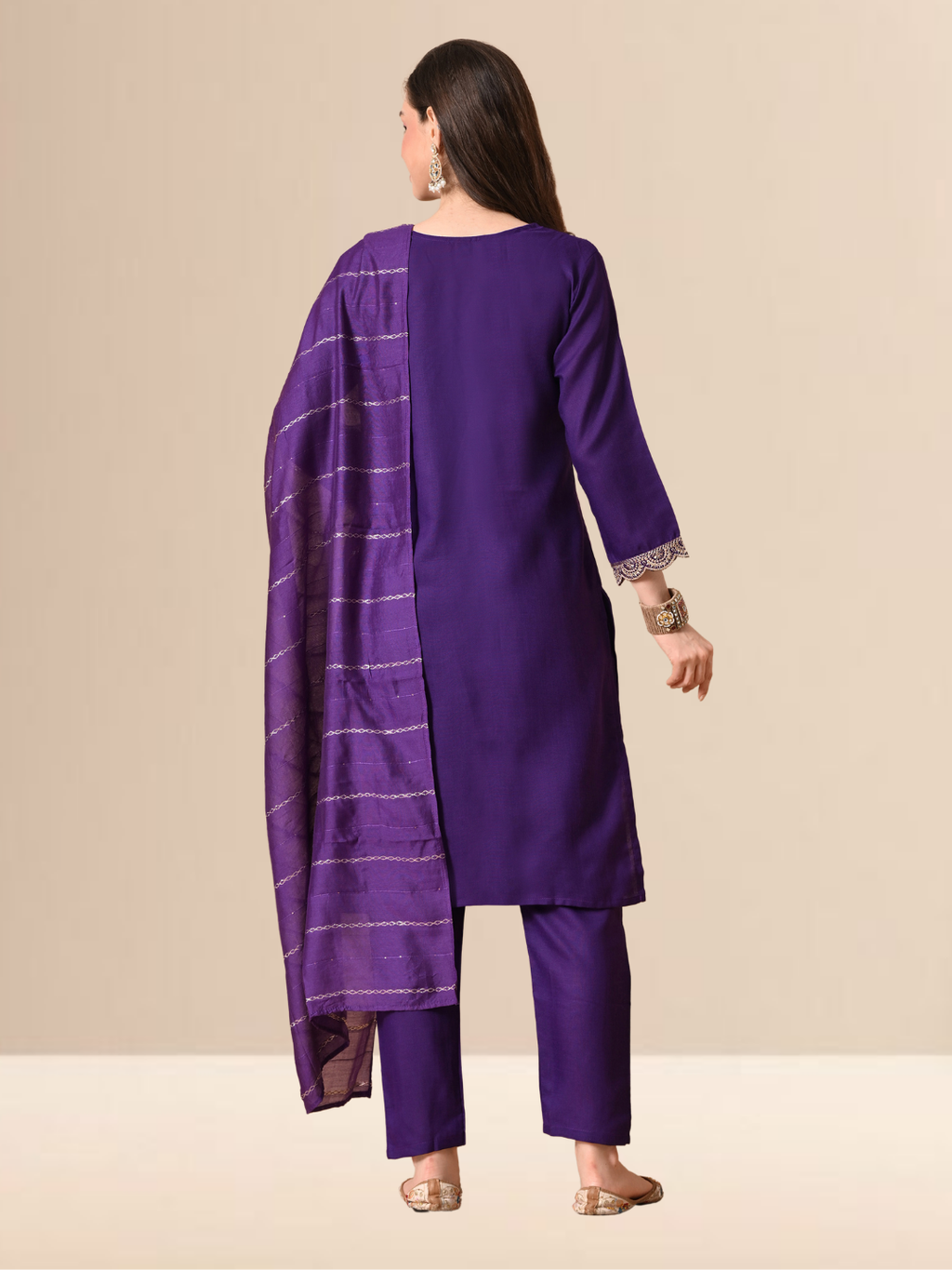 A woman wearing a royal purple straight-cut cotton blend kurta with gold V-neck embroidery, matching trousers, and a purple patterned dupatta.