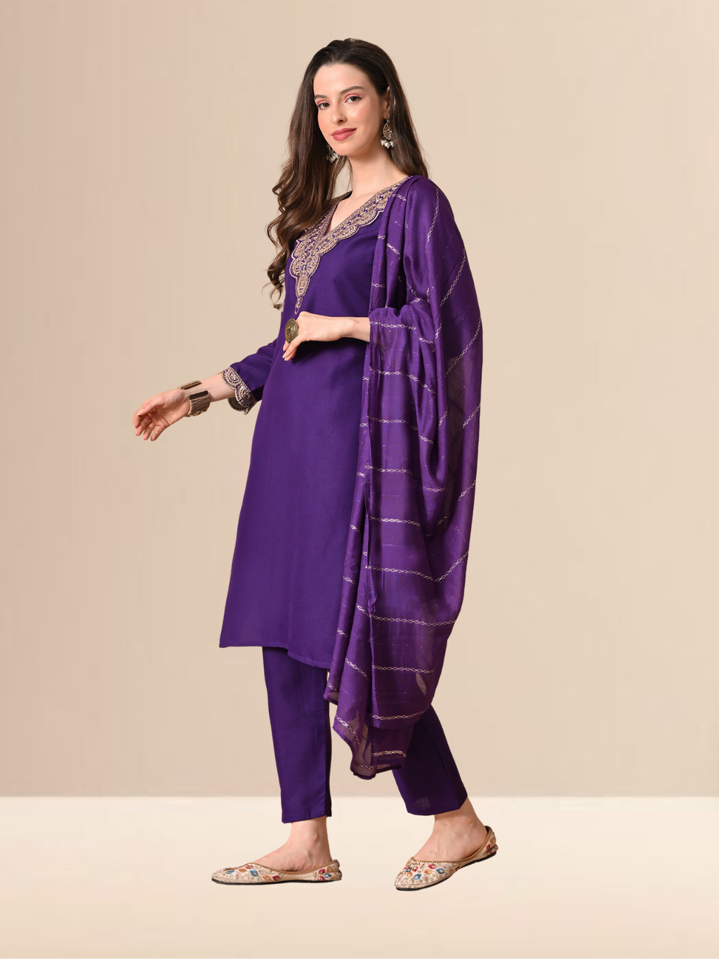A woman wearing a royal purple straight-cut cotton blend kurta with gold V-neck embroidery, matching trousers, and a purple patterned dupatta.