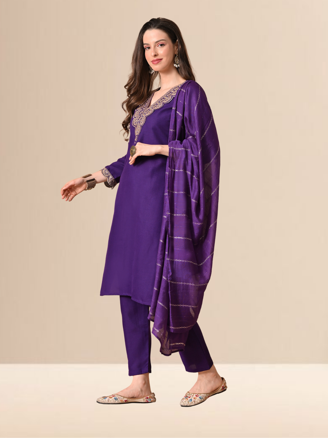 A woman wearing a royal purple straight-cut cotton blend kurta with gold V-neck embroidery, matching trousers, and a purple patterned dupatta.
