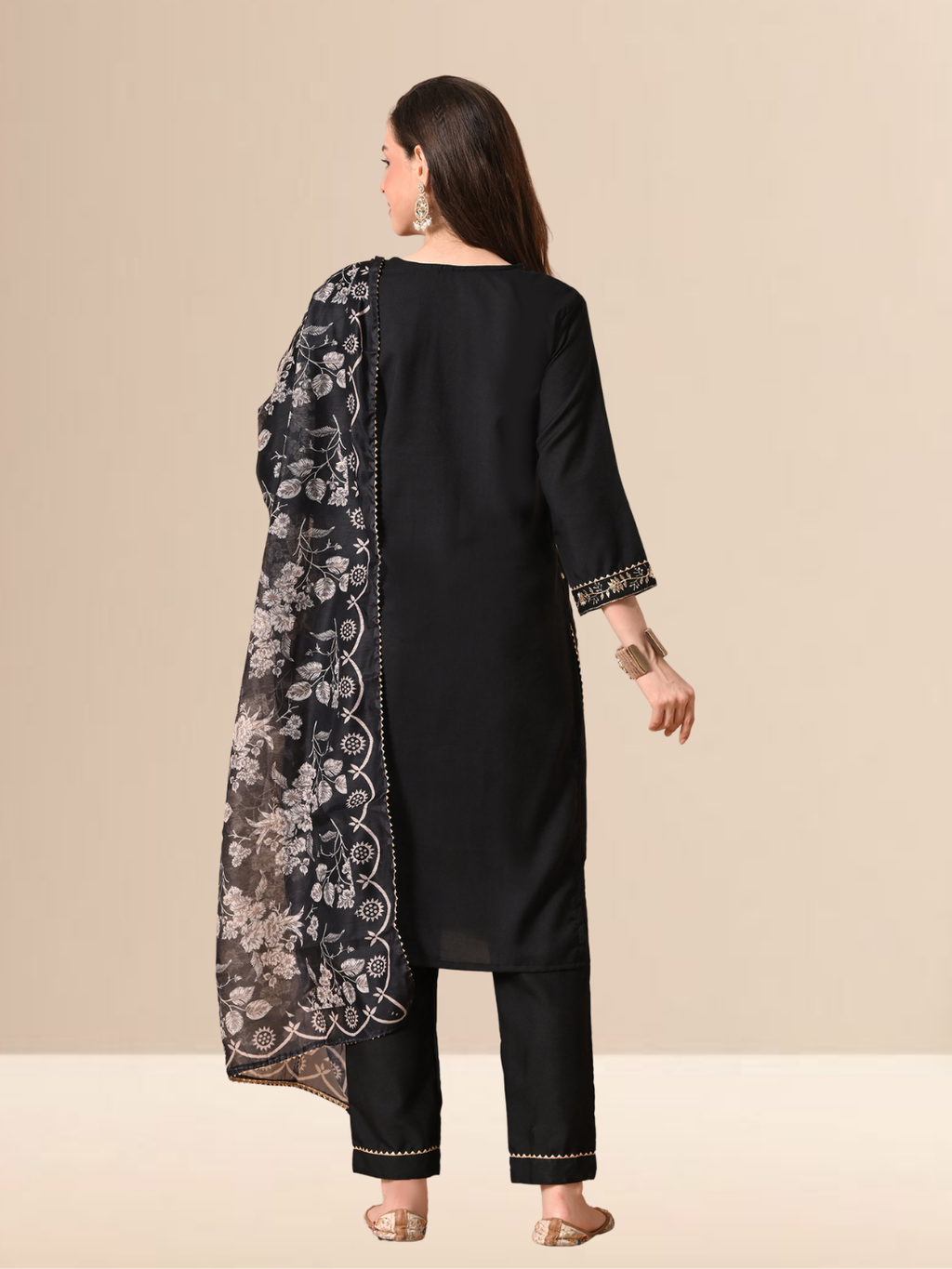 A woman wearing a black cotton blend kurta set with golden embroidery on the neck and a floral printed dupatta.