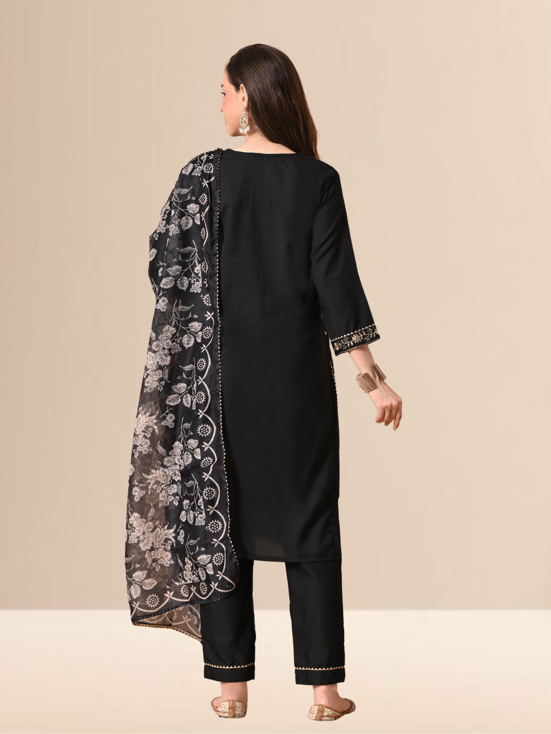 A woman wearing a black cotton blend kurta set with golden embroidery on the neck and a floral printed dupatta.