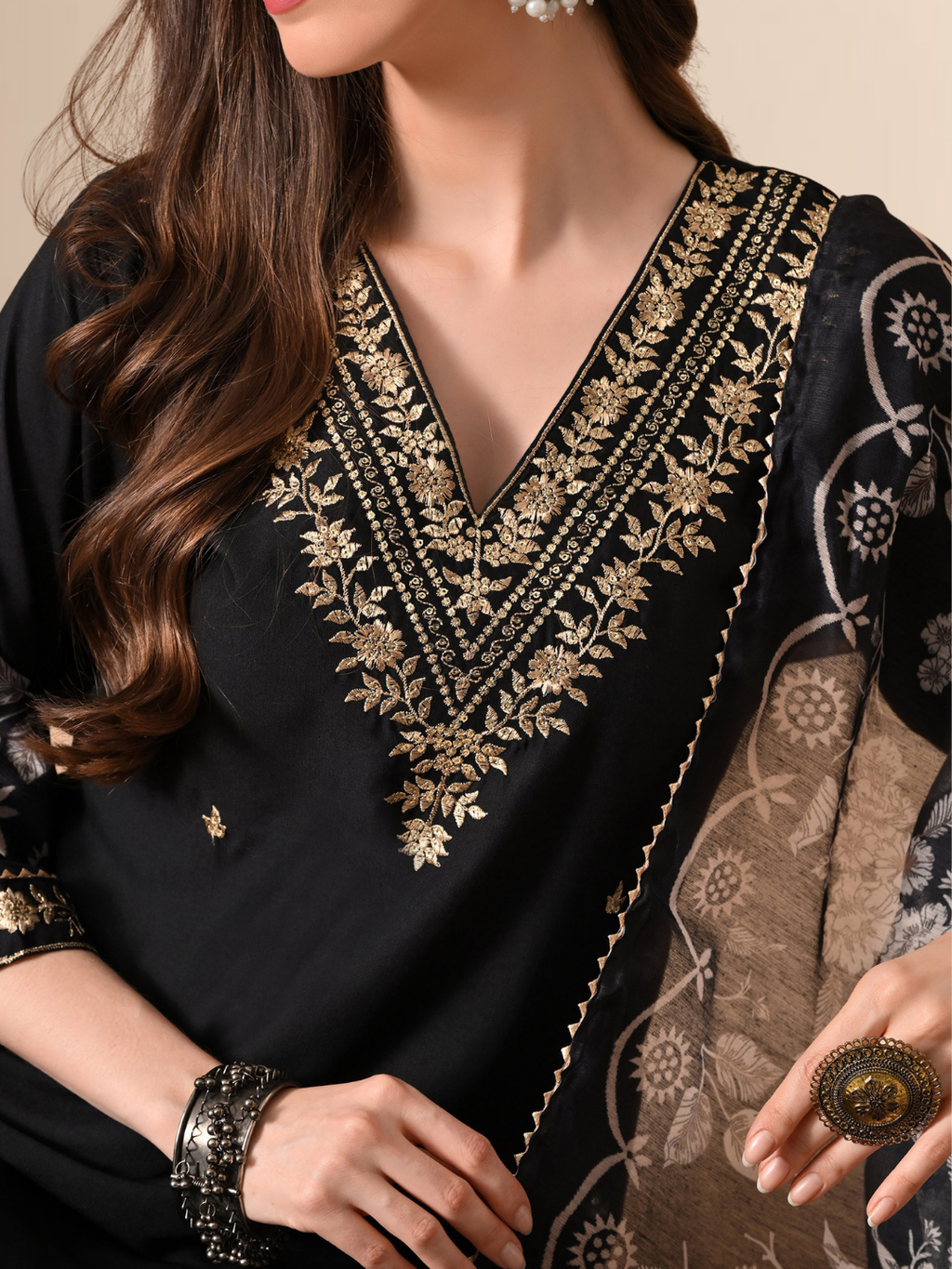 A woman wearing a black cotton blend kurta set with golden embroidery on the neck and a floral printed dupatta.