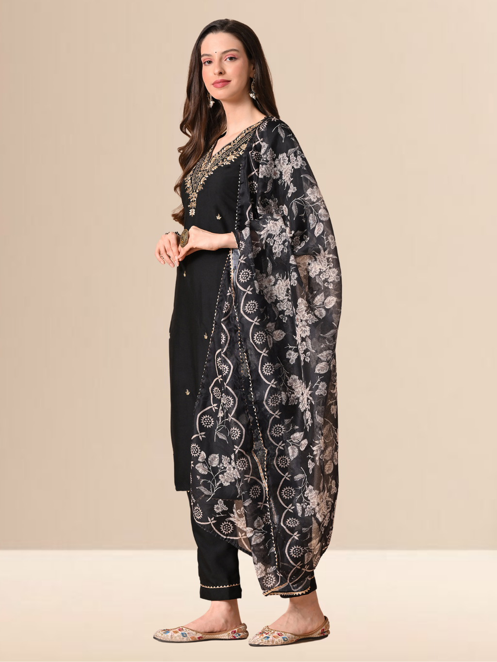 A woman wearing a black cotton blend kurta set with golden embroidery on the neck and a floral printed dupatta.