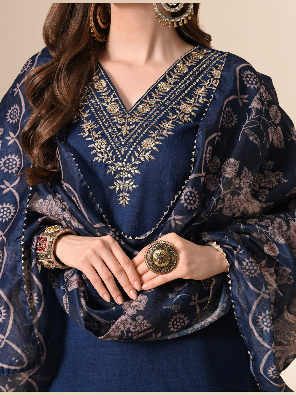 Woman wearing a navy blue cotton blend kurta set with golden V-neck embroidery and a floral printed dupatta.