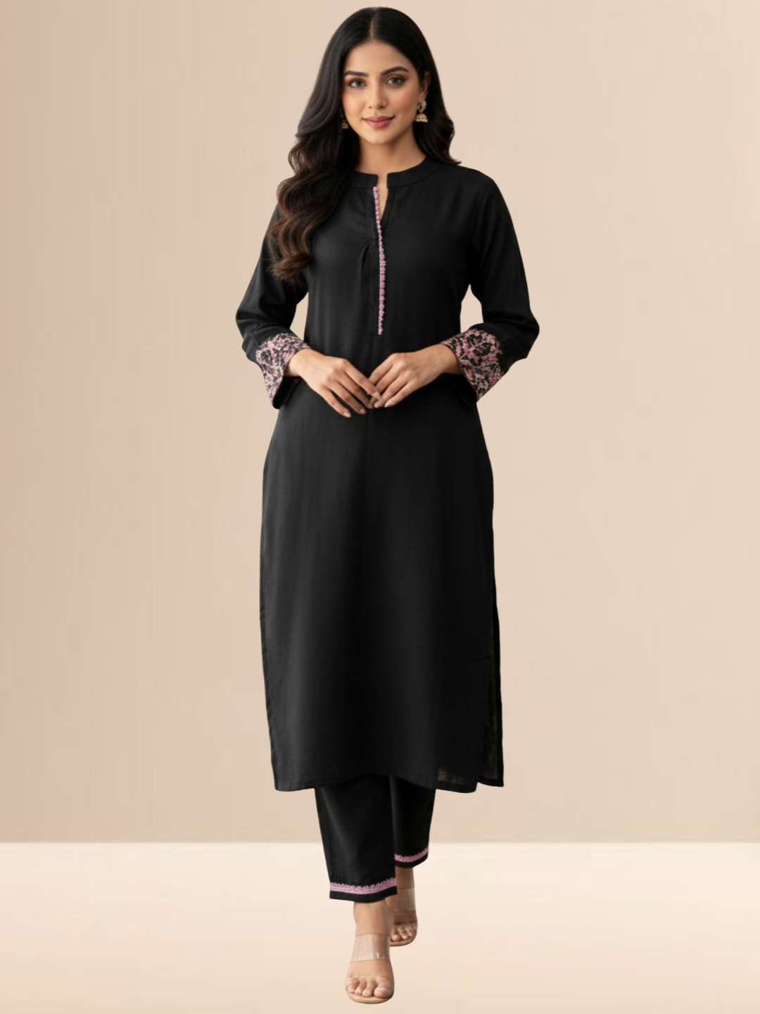 Woman wearing a jet black cotton kurta set with pink floral embroidery on the sleeves and matching lace detailing on the neckline and pants.