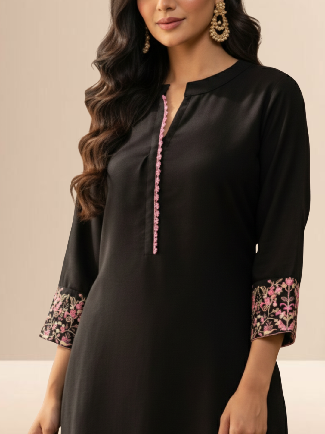 Woman wearing a jet black cotton kurta set with pink floral embroidery on the sleeves and matching lace detailing on the neckline and pants.