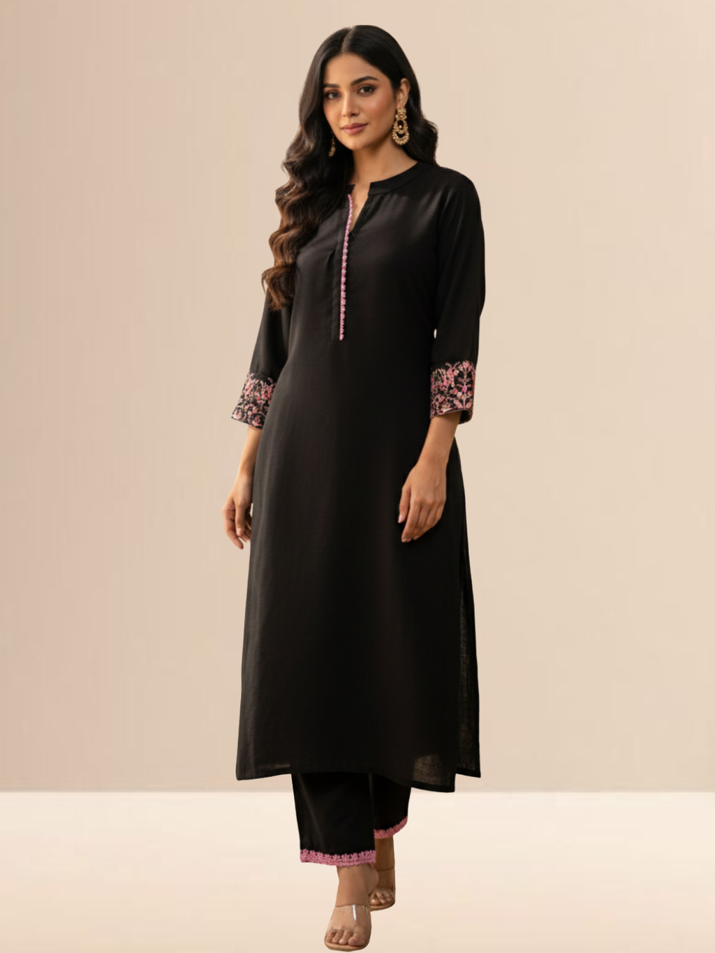 Woman wearing a jet black cotton kurta set with pink floral embroidery on the sleeves and matching lace detailing on the neckline and pants.