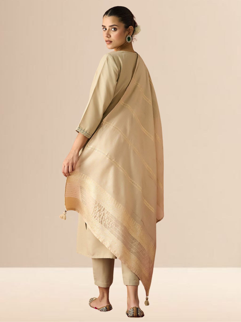 A woman wearing a beige cotton blend kurta set with an embroidered yoke, matching trousers, and a gold-bordered dupatta.