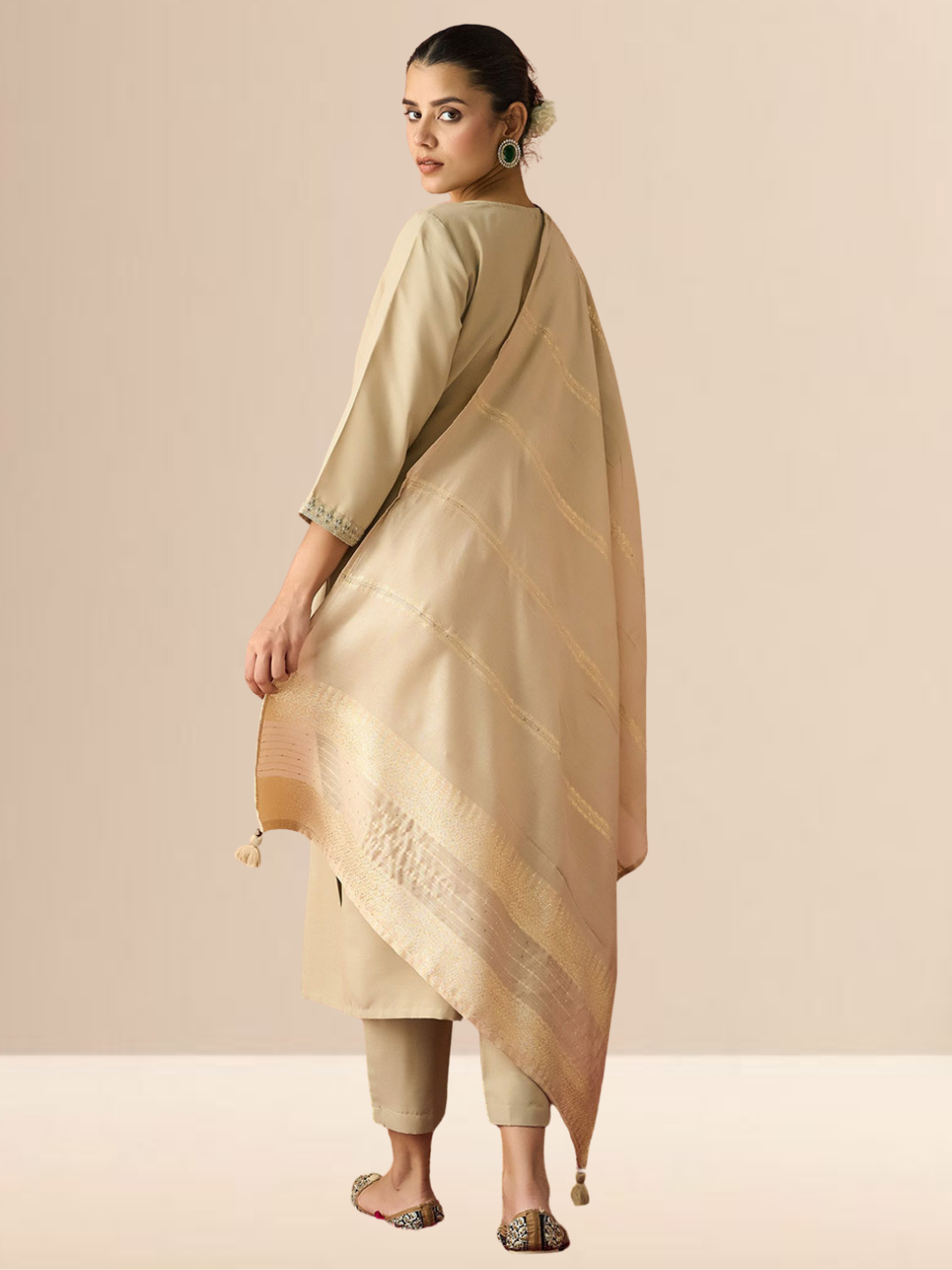 A woman wearing a beige cotton blend kurta set with an embroidered yoke, matching trousers, and a gold-bordered dupatta.