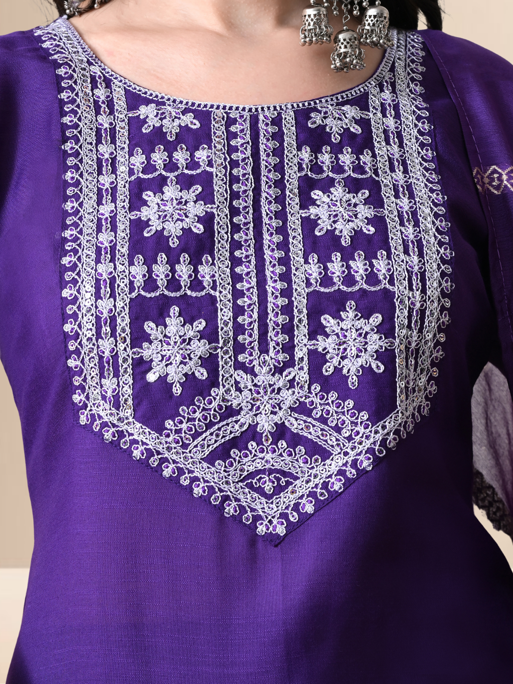 Woman wearing a purple traditional outfit with white embroidery on a beige background