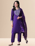 Woman wearing a purple traditional outfit with white embroidery on a beige background