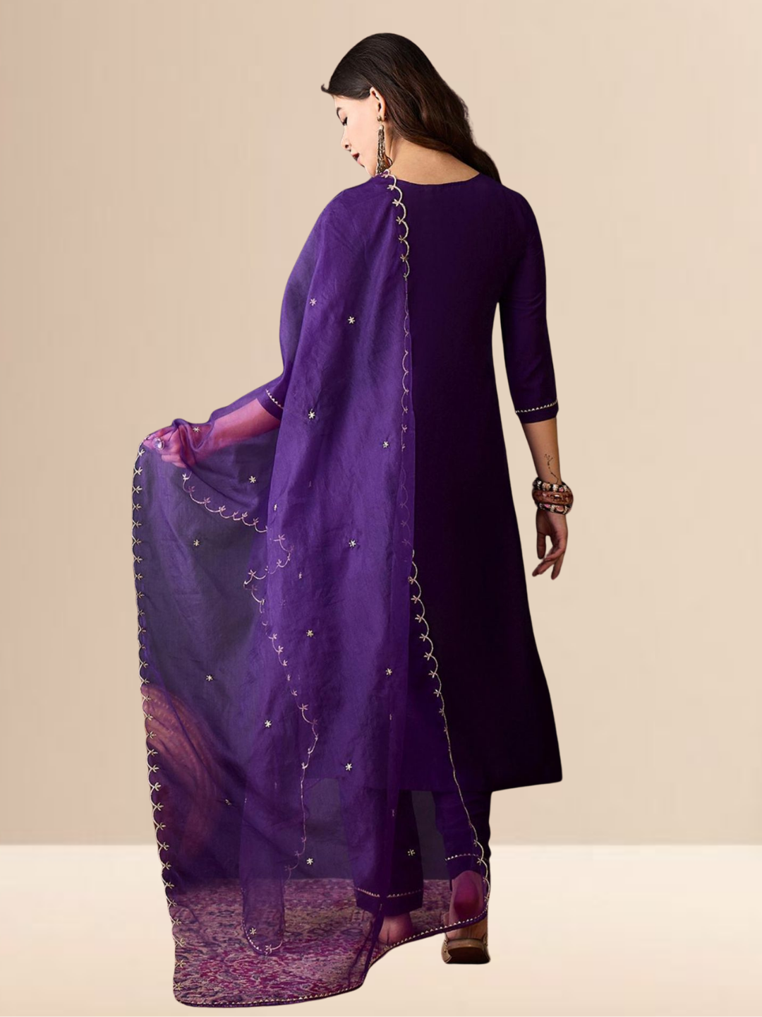 Woman wearing a purple traditional outfit with silver embroidery on a beige background