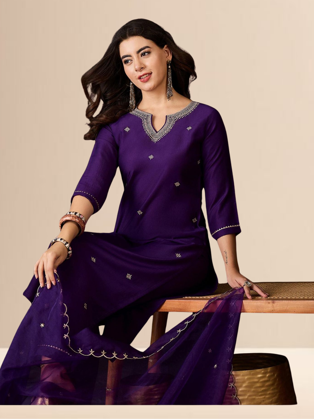 Woman wearing a purple traditional outfit with silver embroidery on a beige background
