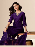 Woman wearing a purple traditional outfit with silver embroidery on a beige background