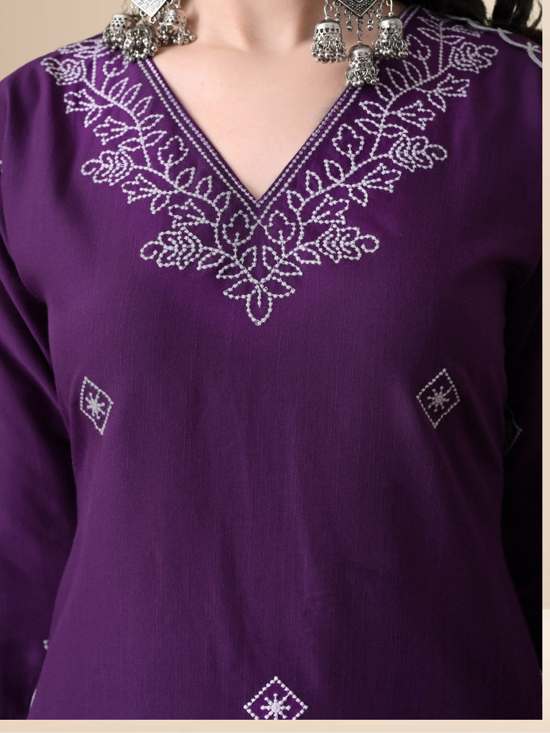 Woman wearing a deep purple cotton blend kurta set with white V-neck embroidery and a sheer scalloped dupatta.
