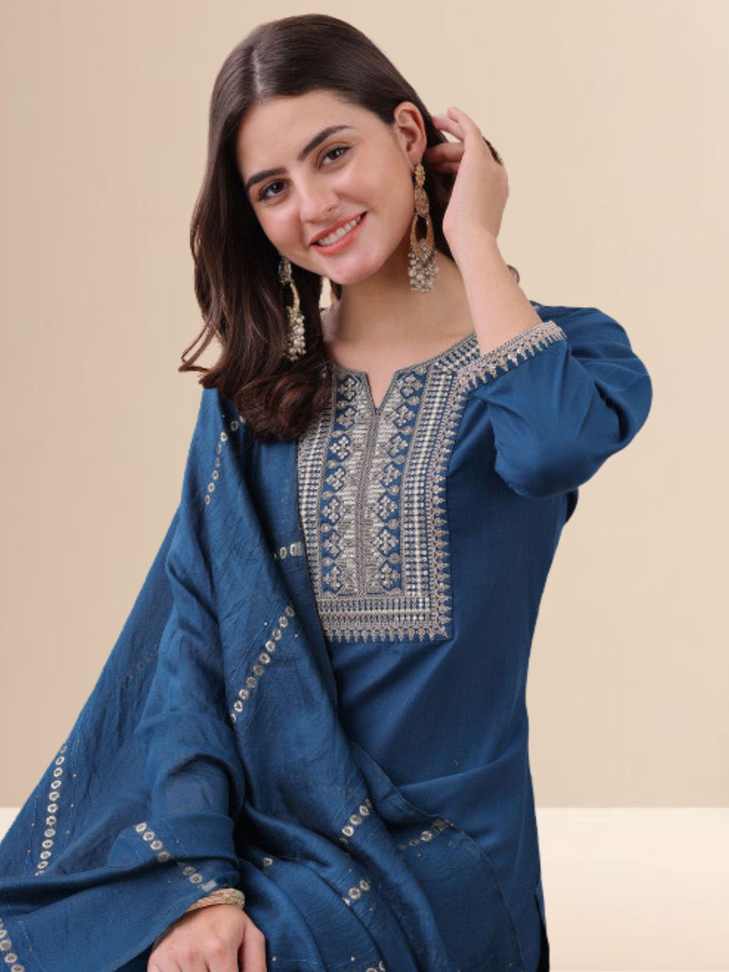 Woman wearing a teal blue cotton blend kurta set with silver embroidery on the neck and a matching striped tasseled dupatta.