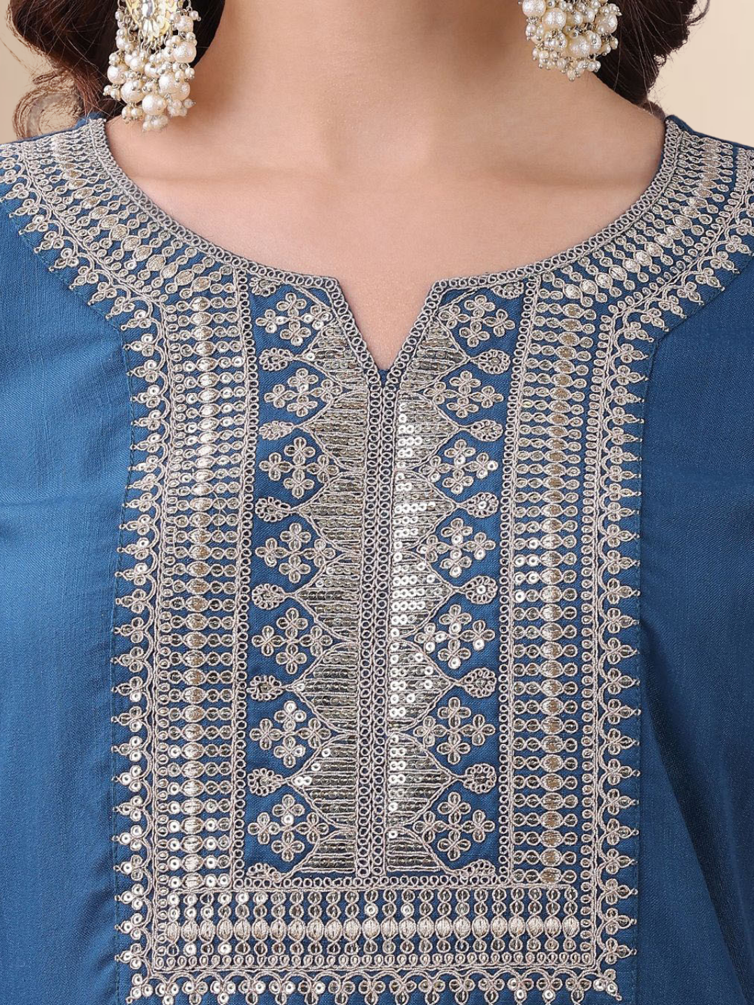 Woman wearing a teal blue cotton blend kurta set with silver embroidery on the neck and a matching striped tasseled dupatta.