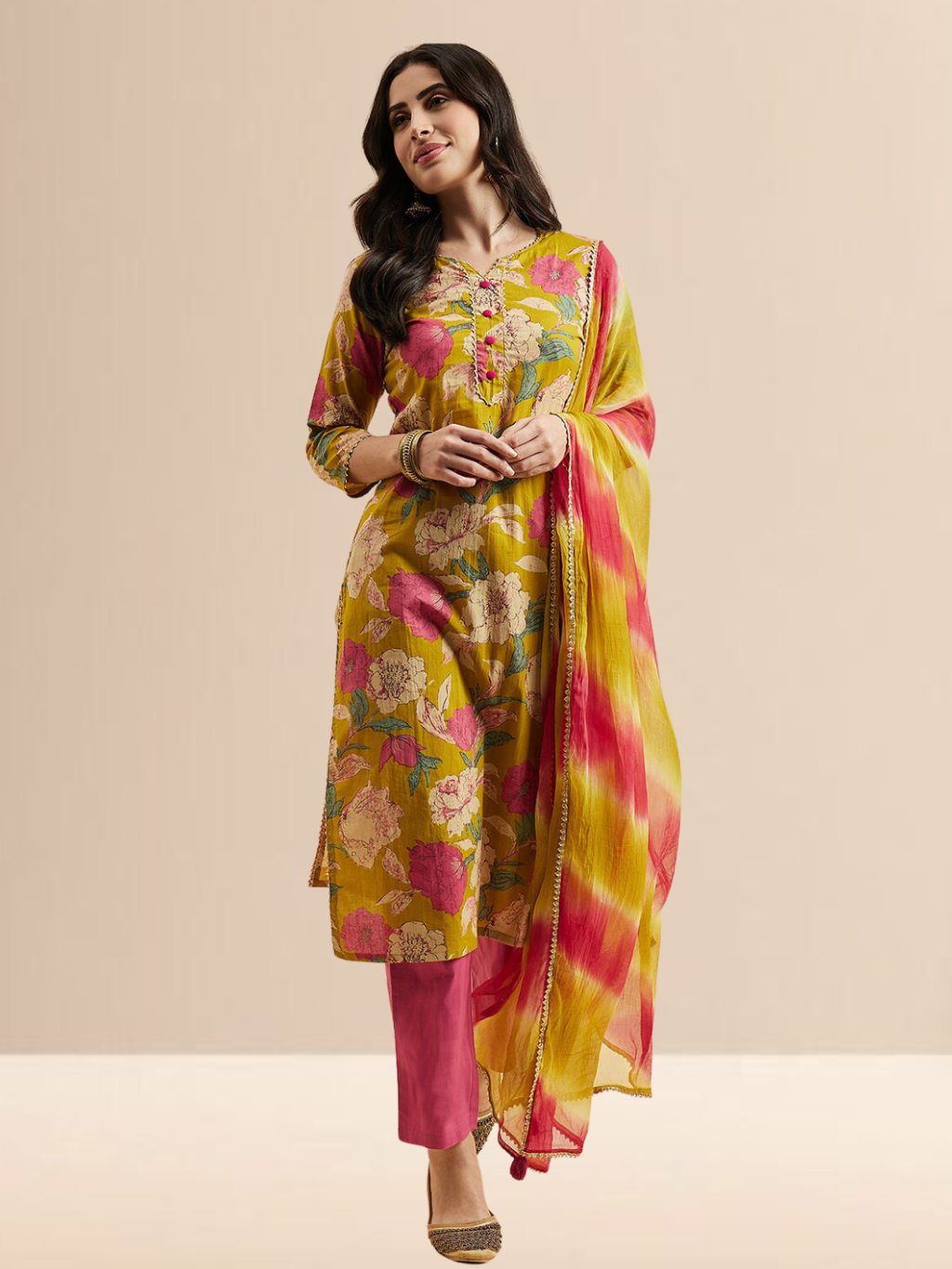  Woman wearing a mustard yellow floral printed kurta with pink pants and a yellow-pink tie-dye dupatta.