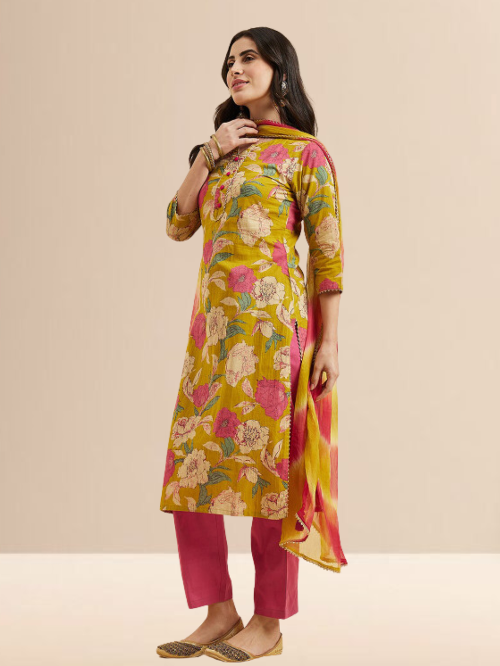 Woman wearing a mustard yellow floral printed kurta with pink pants and a yellow-pink tie-dye dupatta.