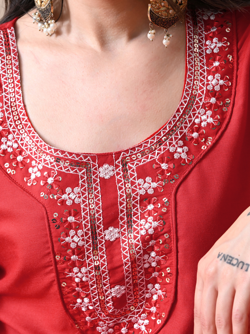 Woman wearing a radiant red blend kurta with white floral embroidery and sequins on the neck, matching red pants, and a sheer red chiffon dupatta.