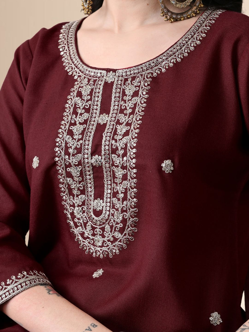 Woman wearing a maroon embroidered cotton kurta set with a floral organza dupatta and matching pants for festive or daily wear.