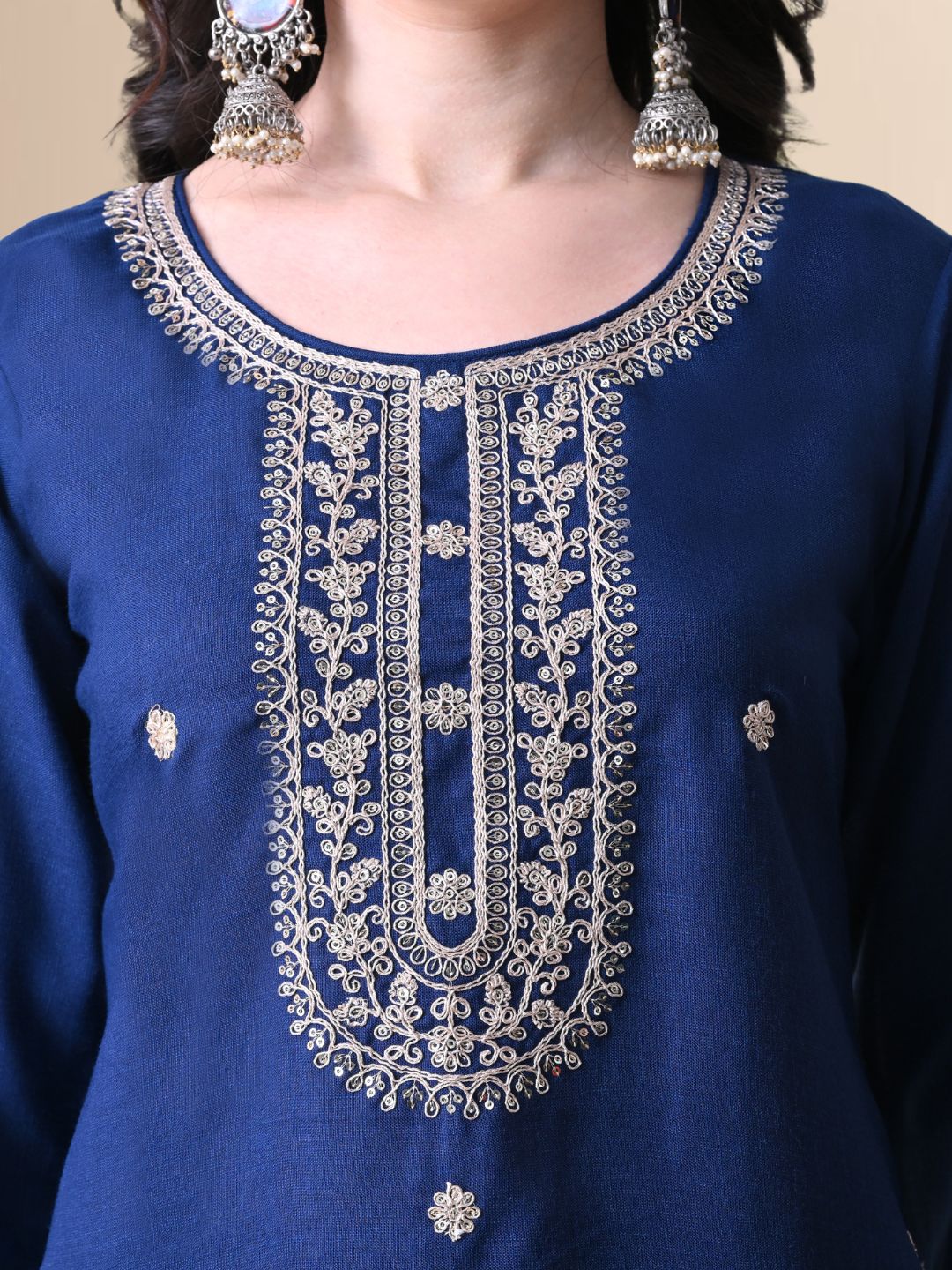 A woman posing in a royal blue embroidered cotton kurta set with matching pants and a light blue floral organza dupatta from The Desi Cloth.