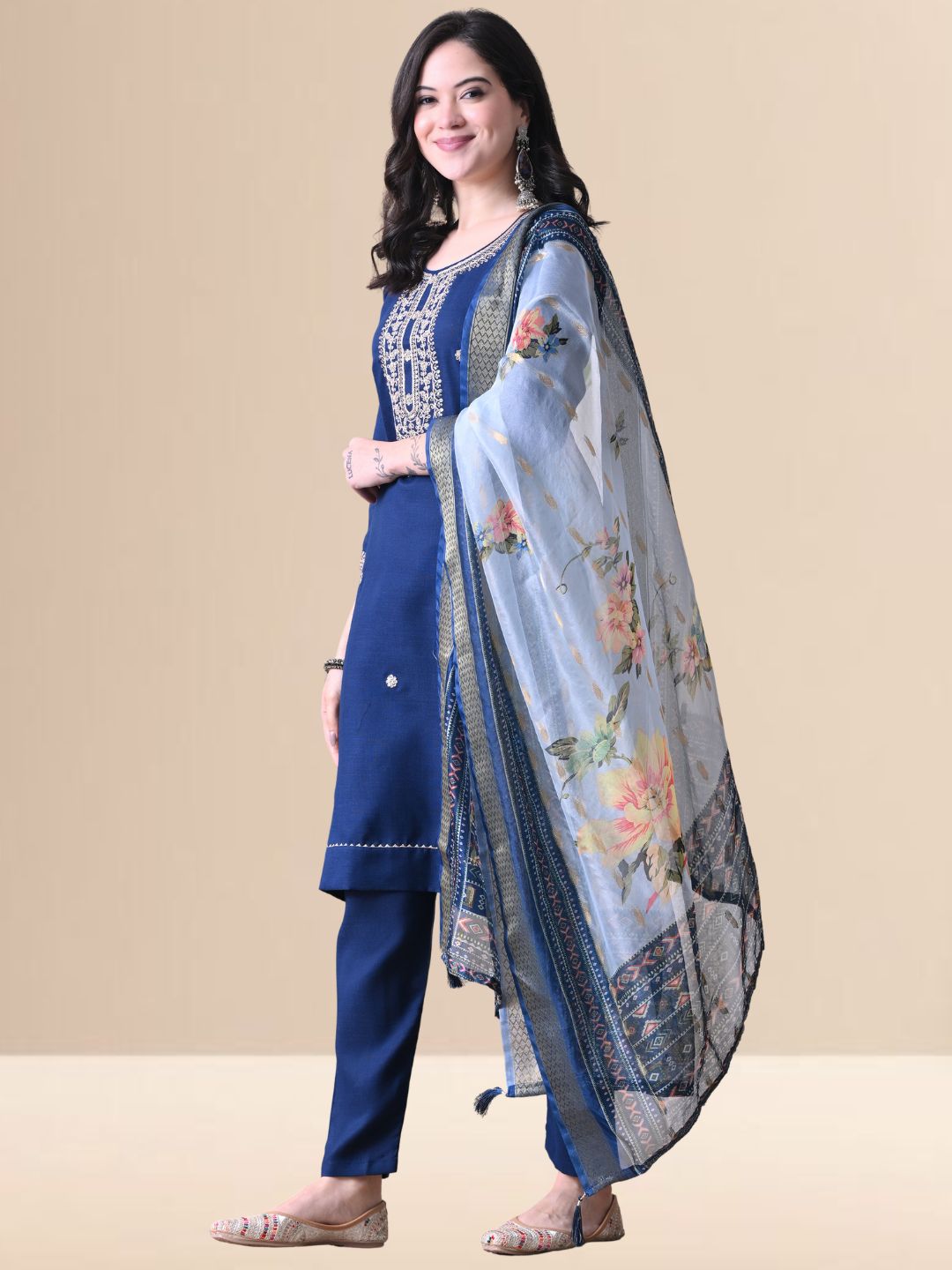 A woman posing in a royal blue embroidered cotton kurta set with matching pants and a light blue floral organza dupatta from The Desi Cloth.