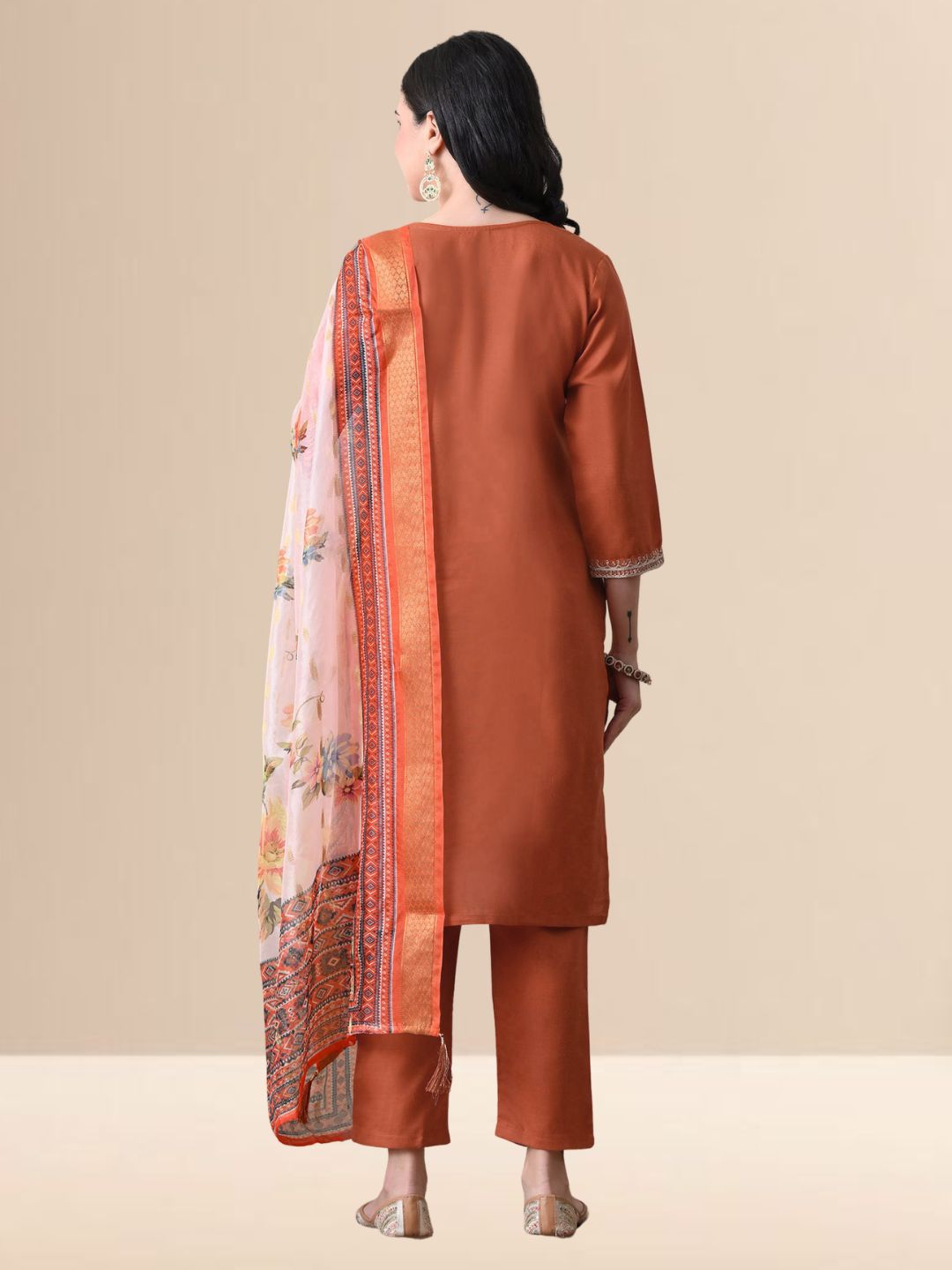 A woman wearing a rust-colored cotton kurta set with white yoke embroidery, matching rust trousers, and a white floral printed dupatta from The Desi Cloth.