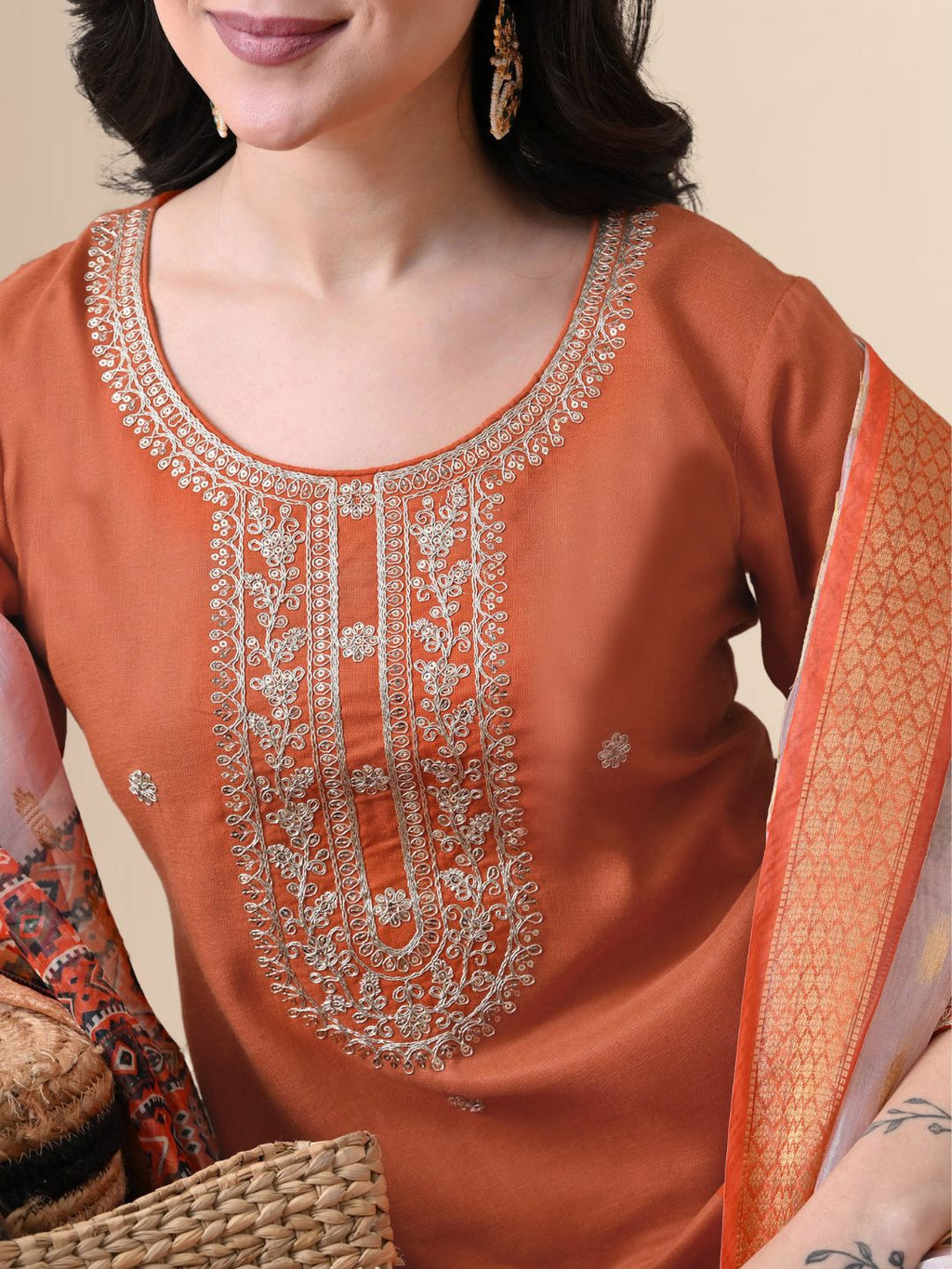 A woman wearing a rust-colored cotton kurta set with white yoke embroidery, matching rust trousers, and a white floral printed dupatta from The Desi Cloth.