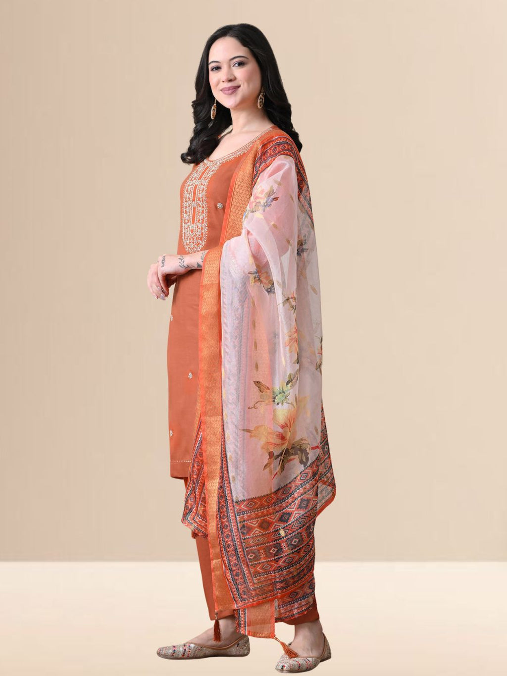 A woman wearing a rust-colored cotton kurta set with white yoke embroidery, matching rust trousers, and a white floral printed dupatta from The Desi Cloth.
