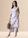 A woman wearing a white sleeveless kurta with pink floral prints and V-neck lace detail, paired with matching wide-leg floral pants from The Desi Cloth.