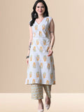 A woman wearing a sleeveless white cotton kurta with yellow and orange floral prints and a lace-trimmed V-neck, paired with matching printed wide-leg pants from The Desi Cloth.