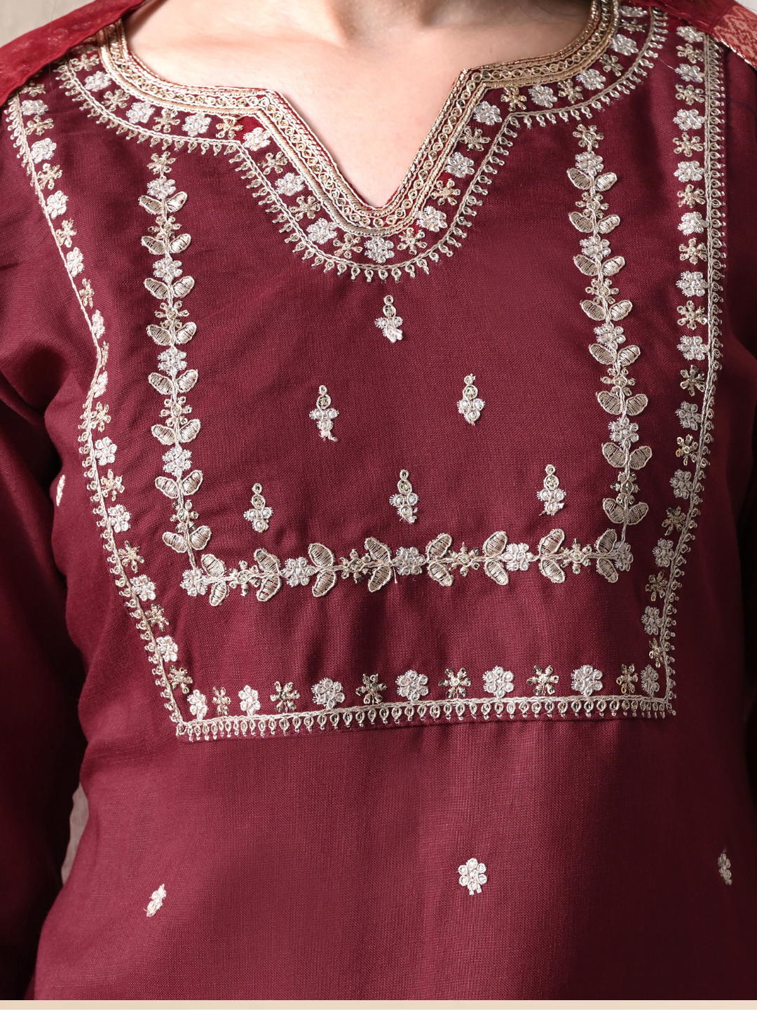 Woman wearing a maroon cotton blend kurta set with intricate silver embroidery on the yoke and a matching striped -style dupatta.